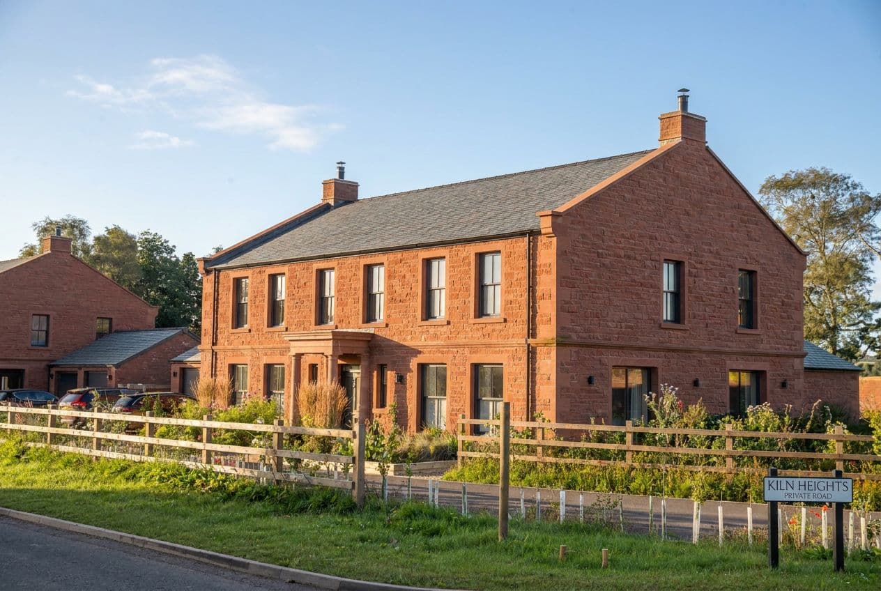 Morning sun on the red sandstone homes at the Kiln Heights entrance, beside the private road sign