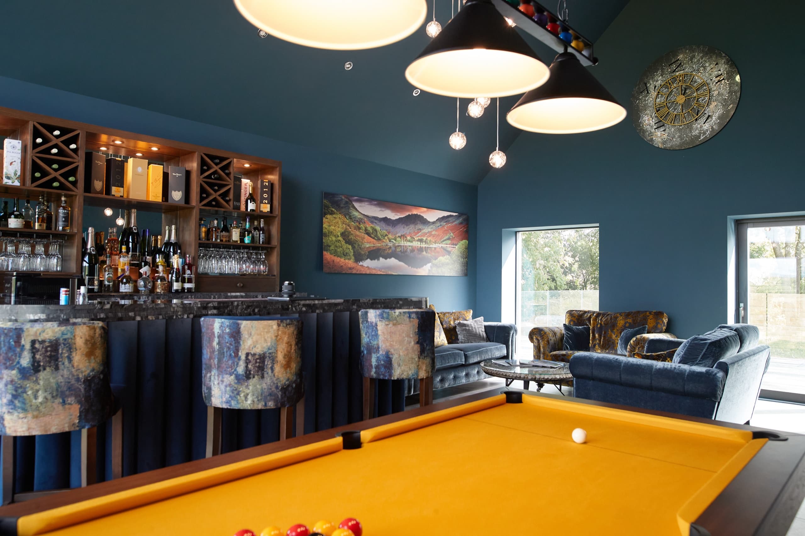 A games room and bar with pool table and velvet seating