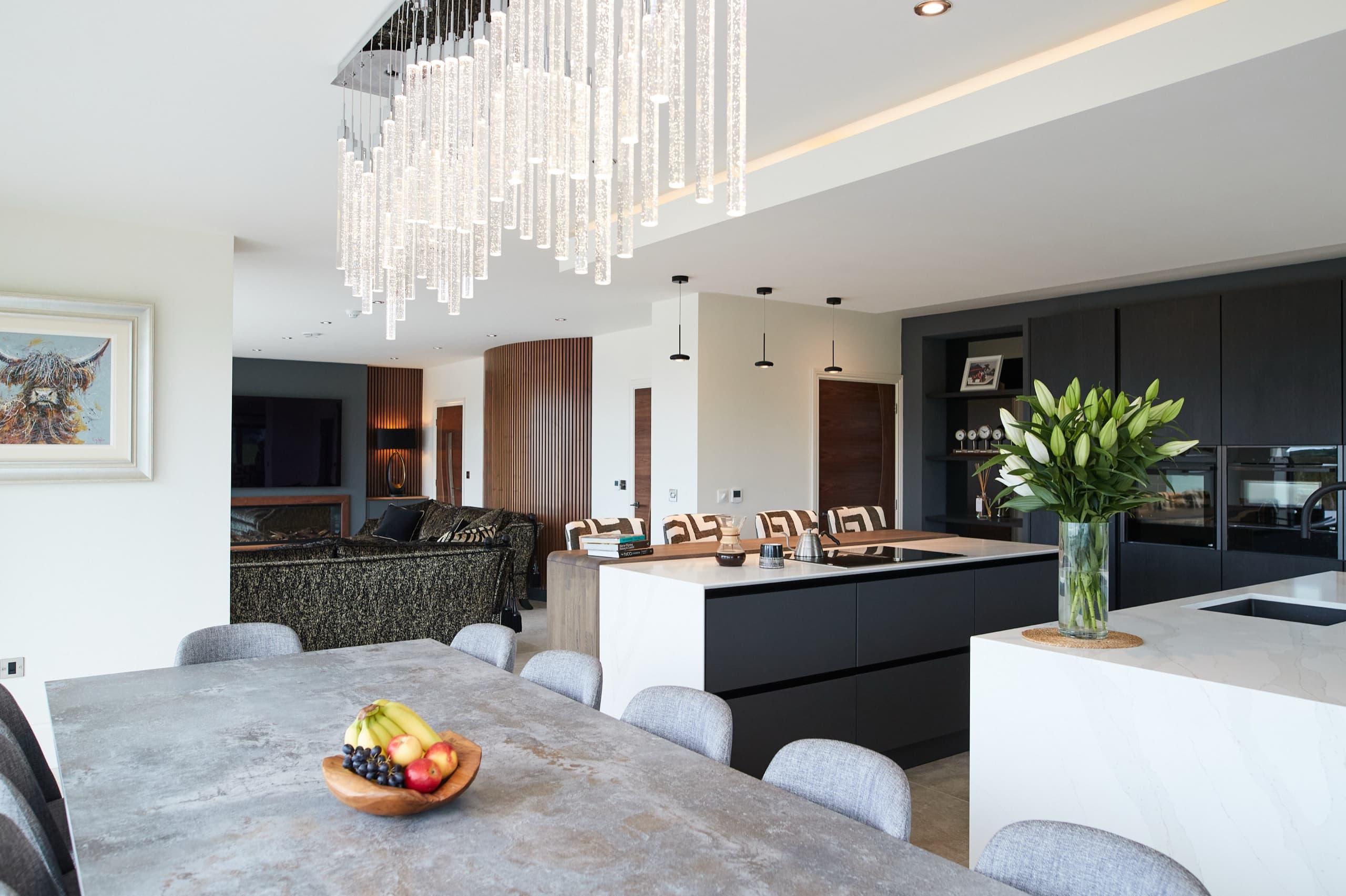 Open-plan kitchen and dining with a marble island and statement crystal pendant
